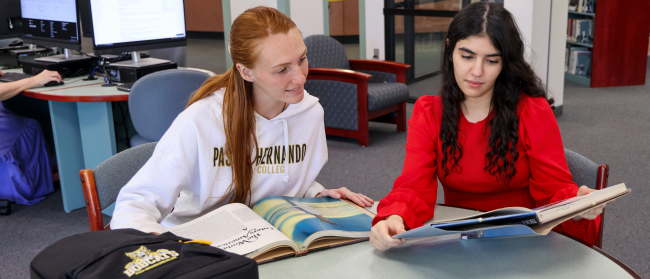 Two female students looking at a book.